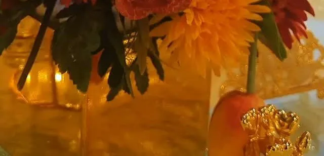 Orange and yellow flowers in a gold vase in warm evening light
